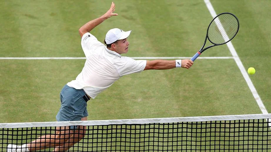 Arthur Fery stretches to play a backhand volley