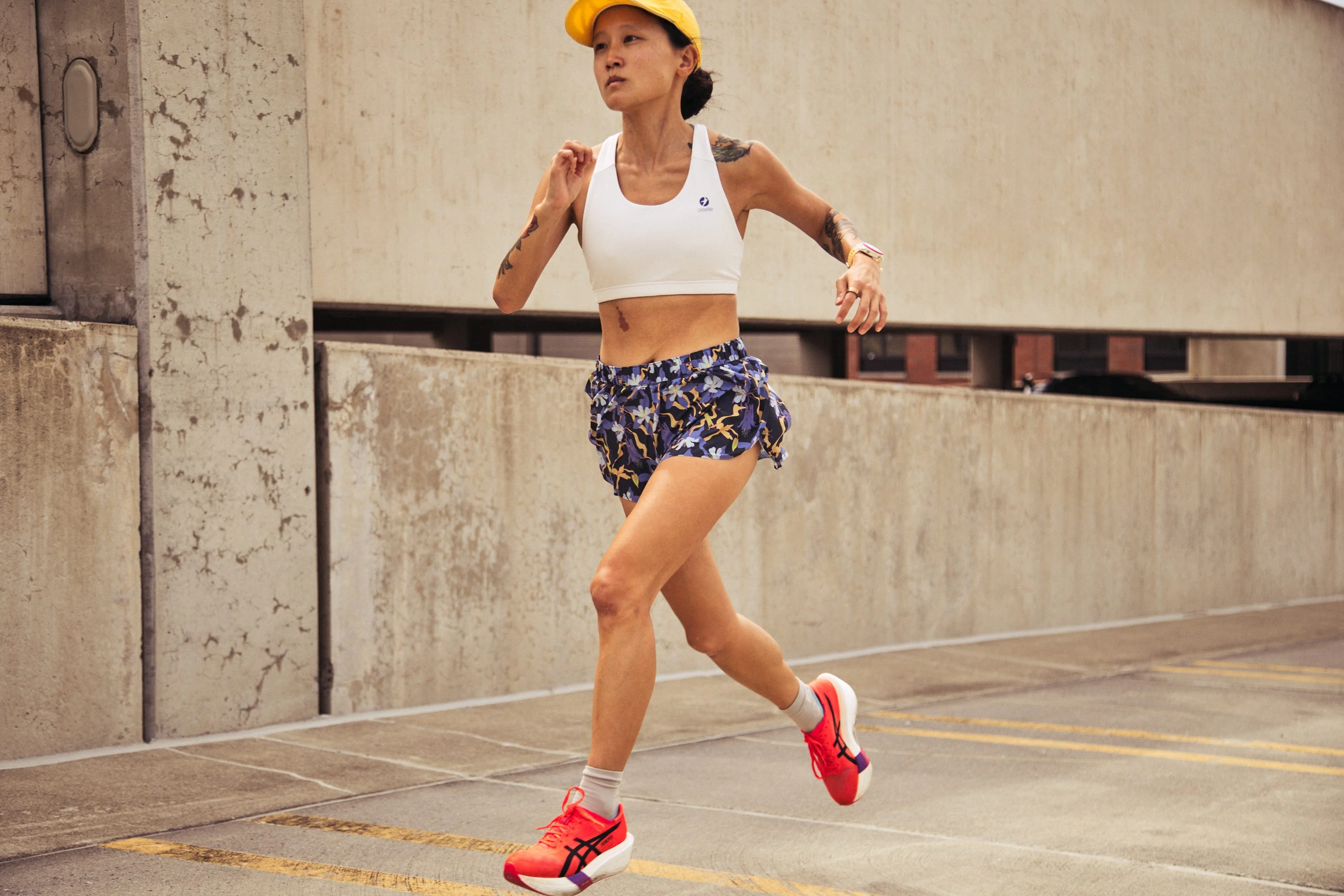 Person running outdoors wearing athletic gear and a yellow cap.