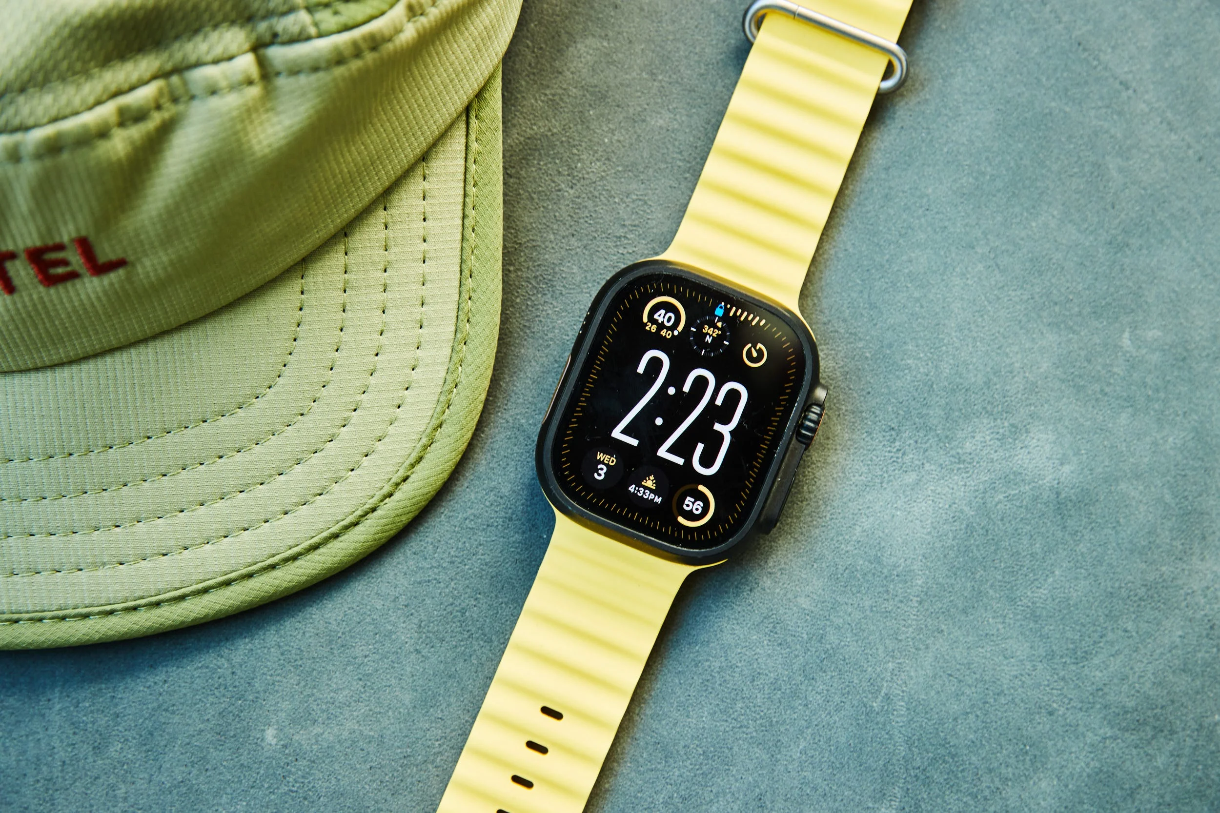 Wristwatch displaying time with a light yellow band next to a green cap