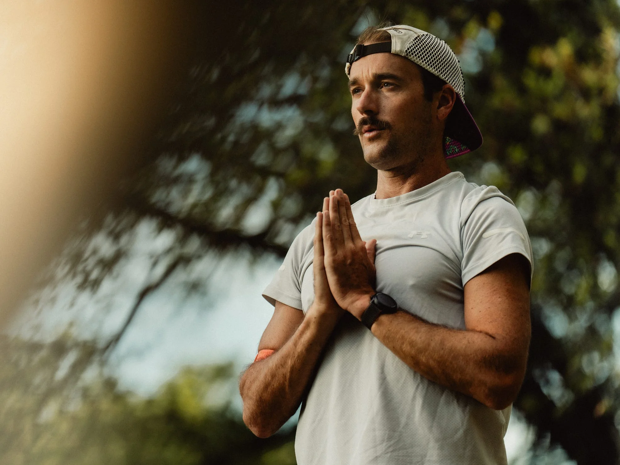 Person outdoors practicing meditation or yoga with hands in prayer position.