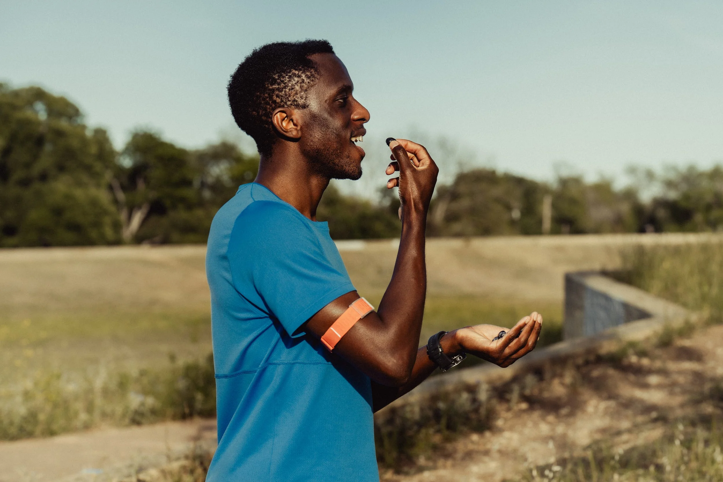A runner in a blue shirt eating blueberries outdoors.