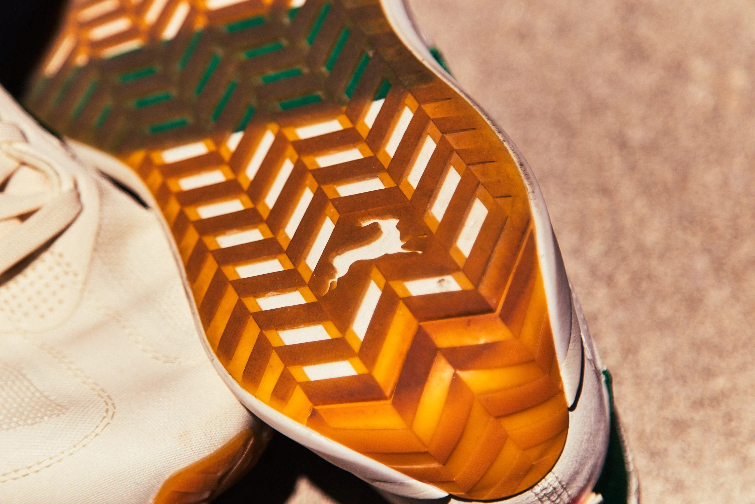 Detailed view of the sole of a sneaker featuring a geometric pattern and a logo. Detailed view of the sole of a sneaker featuring a geometric pattern and a logo.