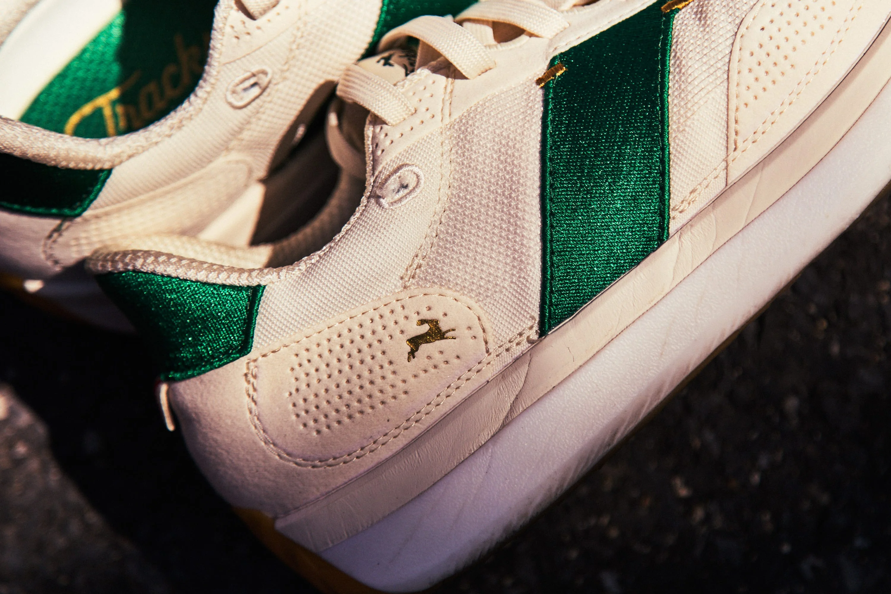 Close-up of a stylish white sneaker with green accents and a textured finish. Close-up of a stylish white sneaker with green accents and a textured finish.