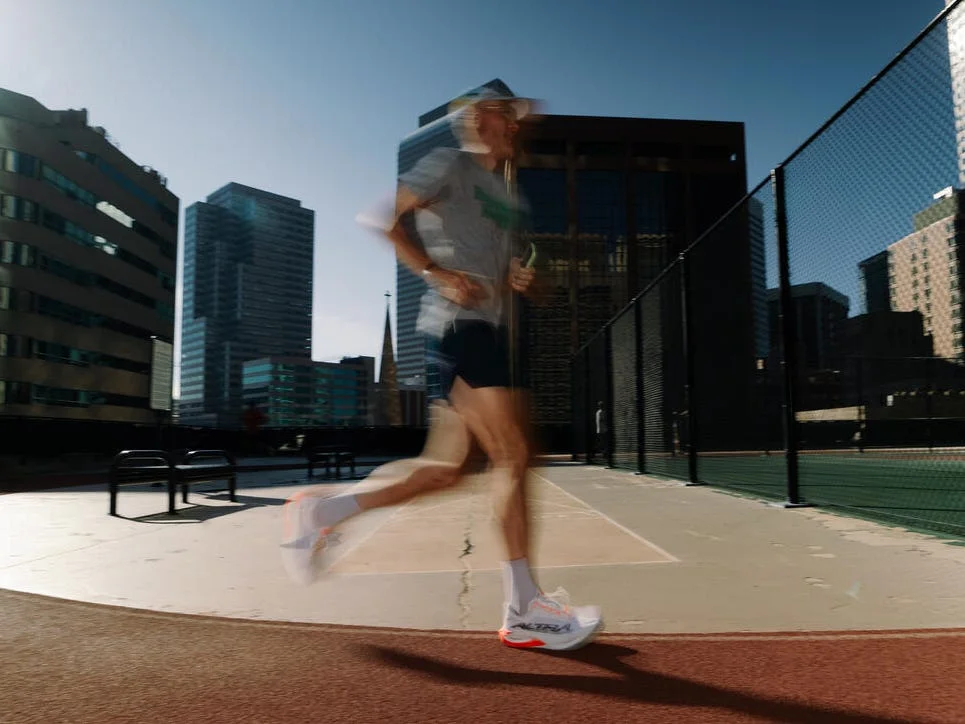 Blurred motion of a runner on a track with city buildings in the background and bright sunlight. Blurred motion of a runner on a track with city buildings in the background and bright sunlight.