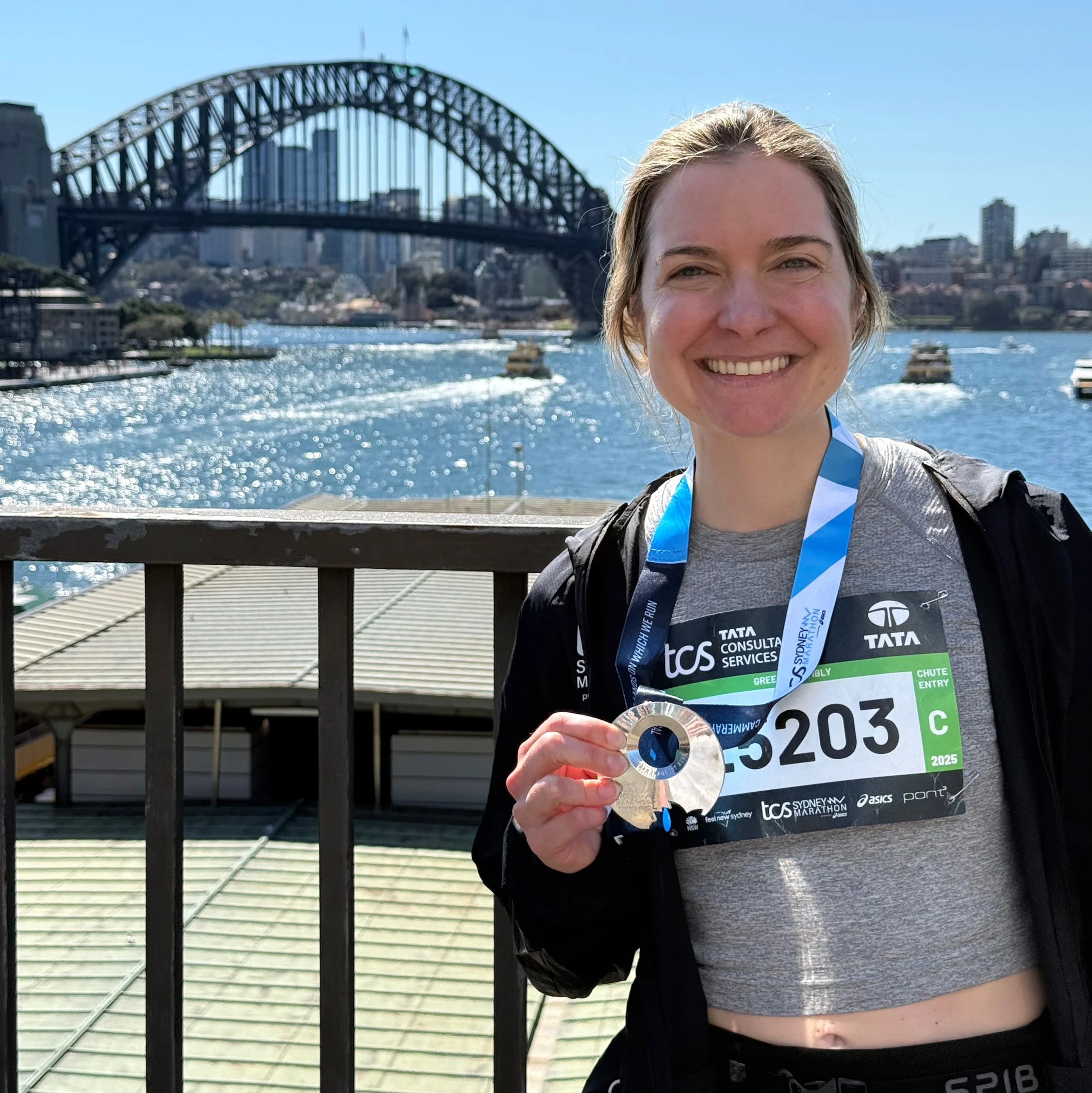a runner posing for a photo holding up their medal a runner posing for a photo holding up their medal