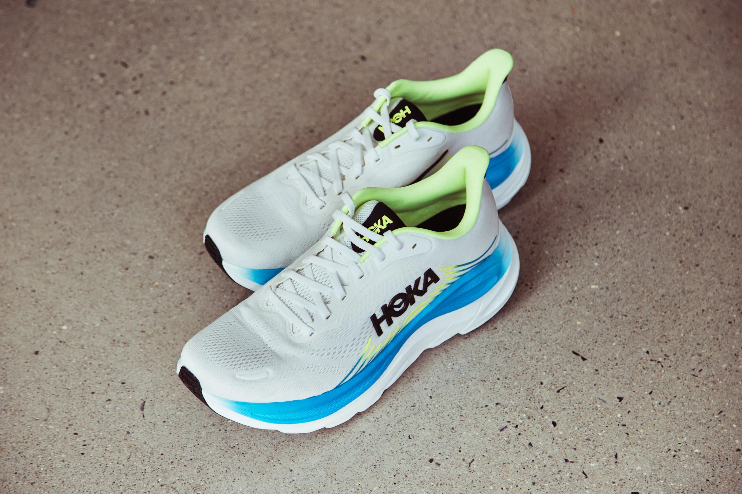 White athletic shoes with blue accents and lime green details on a concrete surface. White athletic shoes with blue accents and lime green details on a concrete surface.