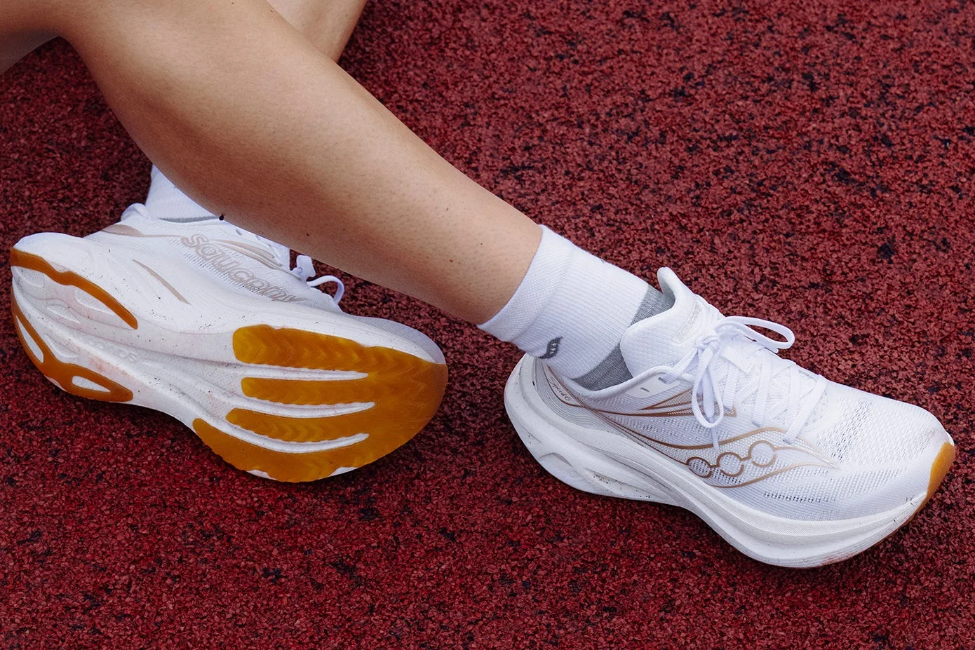 Athletes resting on a track, showcasing white running shoes with vibrant yellow accents. Athletes resting on a track, showcasing white running shoes with vibrant yellow accents.