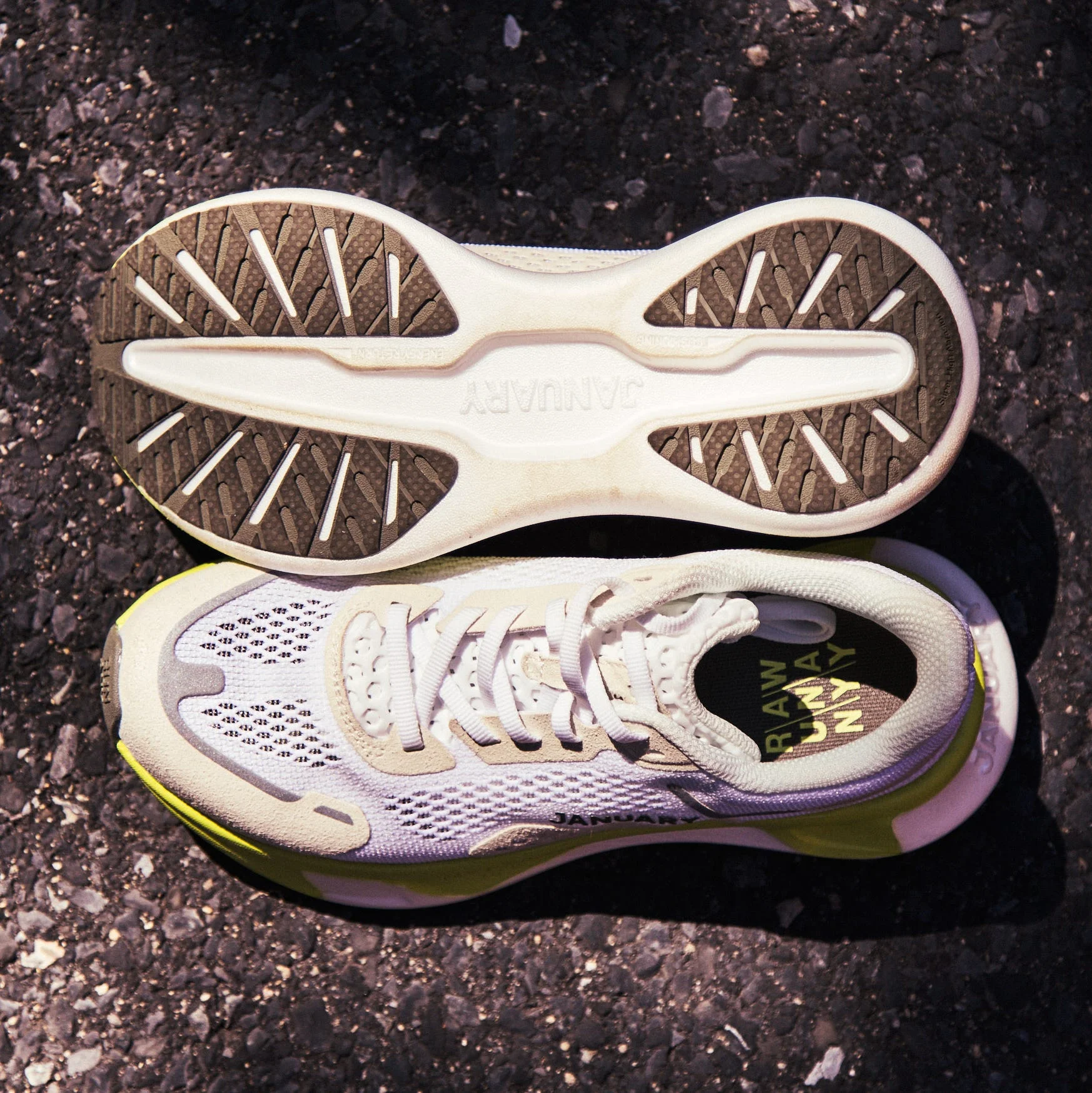 White athletic shoes with textured soles on a dark asphalt surface.