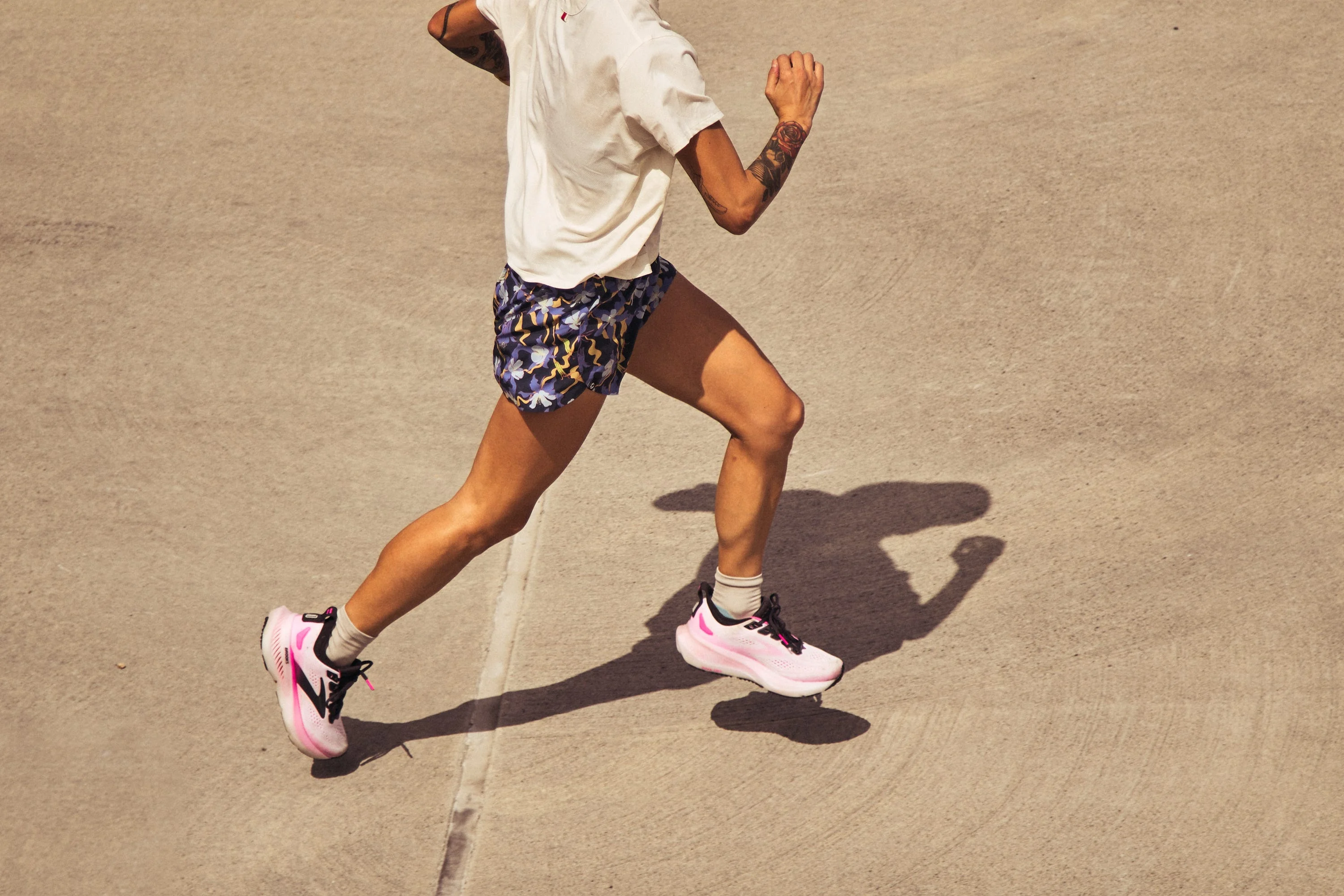 Person running outdoors in colorful shorts and pink sneakers.