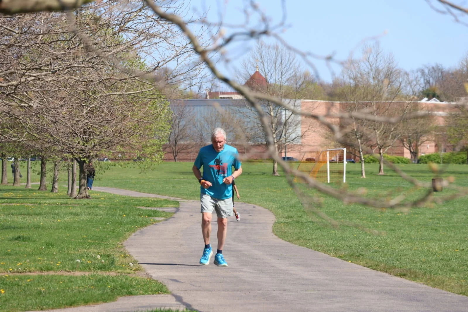 Person jogging on a park path surrounded by trees.